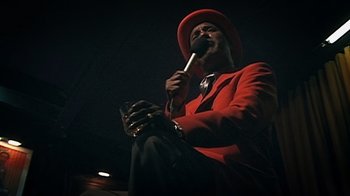 Movie still from “Bamboozled” (2000), directed by Spike Lee – A man in a red jacket and a red hat holding a microphone; Close Up shot, Low angle
