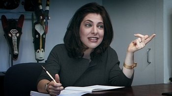 Movie still from “Bamboozled” (2000), directed by Spike Lee – A woman sitting at a table holding a pen and paper; Close Up shot, High angle