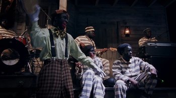 Movie still from “Bamboozled” (2000), directed by Spike Lee – A group of men in prison garb sitting next to each other; Wide shot, High angle