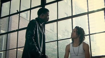 Movie still from “Bamboozled” (2000), directed by Spike Lee – Two young men standing next to each other in front of a window; Medium shot, Over the shoulder angle
