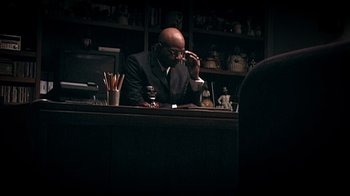 Movie still from “Bamboozled” (2000), directed by Spike Lee – A man sitting at a table with a glass of wine; Medium shot, Low angle