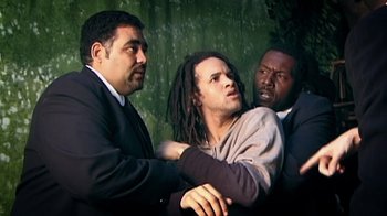 Movie still from “Bamboozled” (2000), directed by Spike Lee – A man being restrained by two other men; Medium shot, Low angle