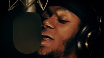 Movie still from “Bamboozled” (2000), directed by Spike Lee – A person with a microphone; Extreme Close Up shot, Low angle