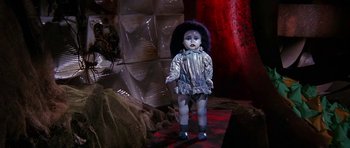 Movie still from “Barbarella” (1968), directed by Roger Vadim – A creepy doll standing in a room with red walls; Medium shot, High angle