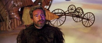 Movie still from “Barbarella” (1968), directed by Roger Vadim – A bearded man in a costume in front of an airplane; Close Up shot, Over the shoulder angle