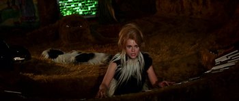 Movie still from “Barbarella” (1968), directed by Roger Vadim – A woman in a black dress and a white furry collar; Medium shot, High angle