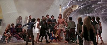 Movie still from “Barbarella” (1968), directed by Roger Vadim – A group of people gathered around a statue of an archangel; Wide shot, High angle