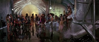 Movie still from “Barbarella” (1968), directed by Roger Vadim – A group of people standing around in a room; Wide shot, High angle