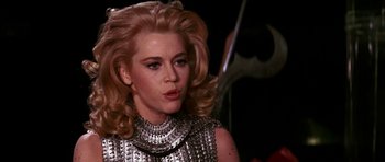 Movie still from “Barbarella” (1968), directed by Roger Vadim – A woman with blonde hair wearing a silver dress; Close Up shot, Over the shoulder angle