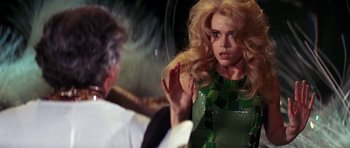 Movie still from “Barbarella” (1968), directed by Roger Vadim – A woman in a green sequined dress looking at a man in a white suit; Medium shot, Over the shoulder angle