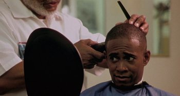 Movie still from “Barbershop” (2002), directed by Tim Story – A man getting his hair cut by a barber; Close Up shot, Over the shoulder angle