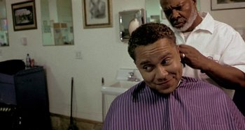 Movie still from “Barbershop” (2002), directed by Tim Story – A man getting his hair combed by a barber; Close Up shot, Over the shoulder angle