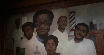 Movie still from “Barbershop” (2002), directed by Tim Story – A mural of a barber shop with a bunch of people; Close Up shot, Low angle