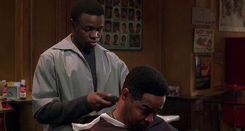 Movie still from “Barbershop” (2002), directed by Tim Story – A man getting his hair cut by another man; Medium shot, Over the shoulder angle