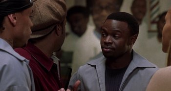 Movie still from “Barbershop” (2002), directed by Tim Story – Two men talking to each other in front of a group of people; Close Up shot, Over the shoulder angle