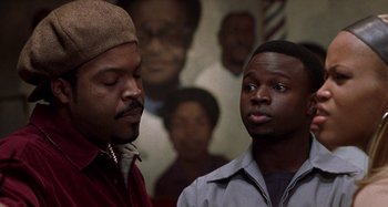 Movie still from “Barbershop” (2002), directed by Tim Story – Two black men standing next to each other in front of a mural; Close Up shot, Over the shoulder angle