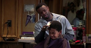 Movie still from “Barbershop” (2002), directed by Tim Story – A man cutting another man's hair in a barber shop; Medium shot, Over the shoulder angle
