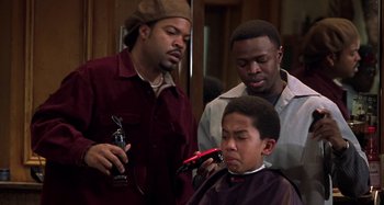Movie still from “Barbershop” (2002), directed by Tim Story – A man getting his hair cut by two other men; Medium shot, Over the shoulder angle