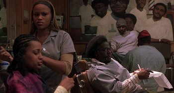 Movie still from “Barbershop” (2002), directed by Tim Story – A group of people sitting in front of a painting; Medium shot, Over the shoulder angle