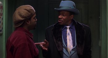 Movie still from “Barbershop” (2002), directed by Tim Story – A man wearing a hat and a tie talking to another man wearing a hat; Medium shot, Over the shoulder angle