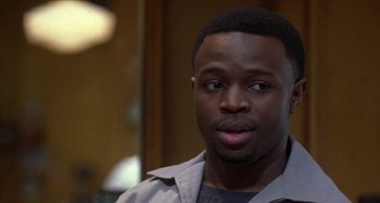 Movie still from “Barbershop” (2002), directed by Tim Story – A person wearing a gray shirt; Close Up shot, Over the shoulder angle