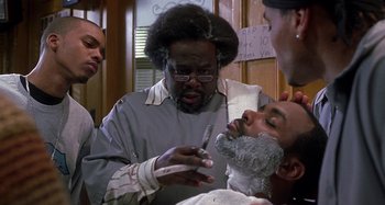 Movie still from “Barbershop” (2002), directed by Tim Story – A man getting his beard shaved by a barber; Close Up shot, Over the shoulder angle