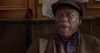 Movie still from “Barbershop” (2002), directed by Tim Story – An older man wearing a plaid shirt and a hat; Close Up shot, Low angle
