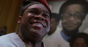 Movie still from “Barbershop” (2002), directed by Tim Story – A person with a hat on smiling; Close Up shot, Low angle