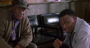 Movie still from “Barbershop” (2002), directed by Tim Story – Two men sitting next to each other in a room; Medium shot, Over the shoulder angle