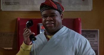 Movie still from “Barbershop” (2002), directed by Tim Story – A man holding up a black phone to his ear; Close Up shot, Low angle