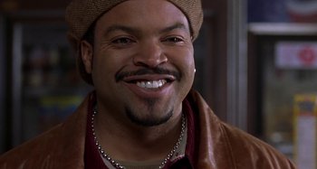 Movie still from “Barbershop” (2002), directed by Tim Story – A person wearing a hat and smiling; Close Up shot, Over the shoulder angle