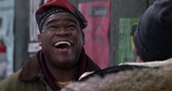 Movie still from “Barbershop” (2002), directed by Tim Story – A man in a red hat and jacket laughing; Close Up shot, Low angle