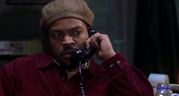 Movie still from “Barbershop” (2002), directed by Tim Story – A man in a hat is talking on a phone; Close Up shot, High angle
