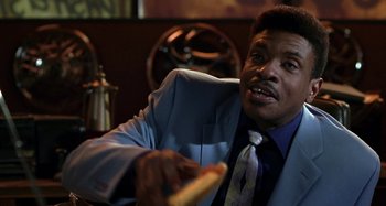 Movie still from “Barbershop” (2002), directed by Tim Story – A man wearing a suit and tie holding a hot dog; Close Up shot, Low angle