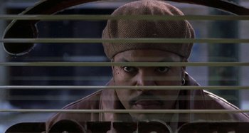 Movie still from “Barbershop” (2002), directed by Tim Story – A person looking through a window blinds; Close Up shot, Low angle