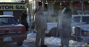 Movie still from “Barbershop” (2002), directed by Tim Story – Two men standing on the side of the road talking to each other; Medium shot, Over the shoulder angle