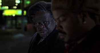 Movie still from “Barbershop” (2002), directed by Tim Story – A man with dreadlocks and glasses is looking at the camera; Close Up shot, Over the shoulder angle