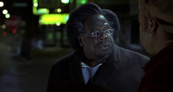Movie still from “Barbershop” (2002), directed by Tim Story – A man in a suit and glasses looking at the camera; Close Up shot, Low angle