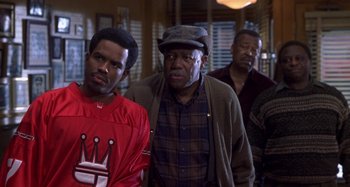 Movie still from “Barbershop” (2002), directed by Tim Story – A group of men standing next to each other in a room; Medium shot, Over the shoulder angle