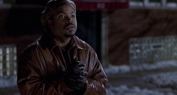 Movie still from “Barbershop” (2002), directed by Tim Story – A man in a brown leather jacket and black leather gloves; Medium shot, Over the shoulder angle