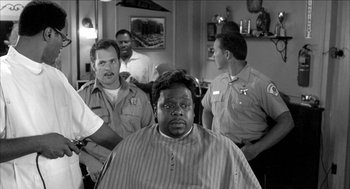 Movie still from “Barbershop 2: Back in Business” (2004), directed by Kevin Rodney Sullivan – A black and white photo of a man getting his hair cut; Medium shot, Over the shoulder angle