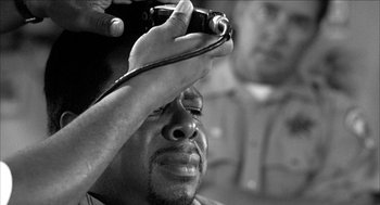 Movie still from “Barbershop 2: Back in Business” (2004), directed by Kevin Rodney Sullivan – A black and white photo of a man holding a camera; Extreme Close Up shot, High angle