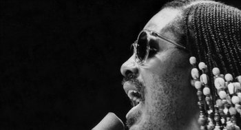 Movie still from “Barbershop 2: Back in Business” (2004), directed by Kevin Rodney Sullivan – A black and white photo of a man singing; Extreme Close Up shot, Low angle