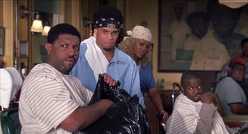 Movie still from “Barbershop 2: Back in Business” (2004), directed by Kevin Rodney Sullivan – A group of people standing around each other holding a bag; Medium shot, Over the shoulder angle