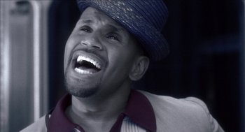 Movie still from “Barbershop 2: Back in Business” (2004), directed by Kevin Rodney Sullivan – A black and white photo of a man with a hat on; Close Up shot, Overhead angle