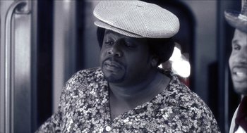 Movie still from “Barbershop 2: Back in Business” (2004), directed by Kevin Rodney Sullivan – A man with a hat is sitting in a room; Close Up shot, Low angle