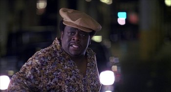 Movie still from “Barbershop 2: Back in Business” (2004), directed by Kevin Rodney Sullivan – A man with a hat on his head is standing in front of a city street; Close Up shot, Low angle