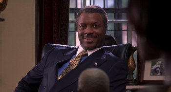 Movie still from “Barbershop 2: Back in Business” (2004), directed by Kevin Rodney Sullivan – A man in a suit and tie sitting in a chair; Close Up shot, Low angle