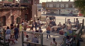 Movie still from “Barbershop 2: Back in Business” (2004), directed by Kevin Rodney Sullivan – A group of people sitting on a wooden deck; Extreme Wide shot, High angle