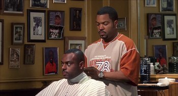 Movie still from “Barbershop 2: Back in Business” (2004), directed by Kevin Rodney Sullivan – A man getting his hair cut by another man; Medium shot, Over the shoulder angle